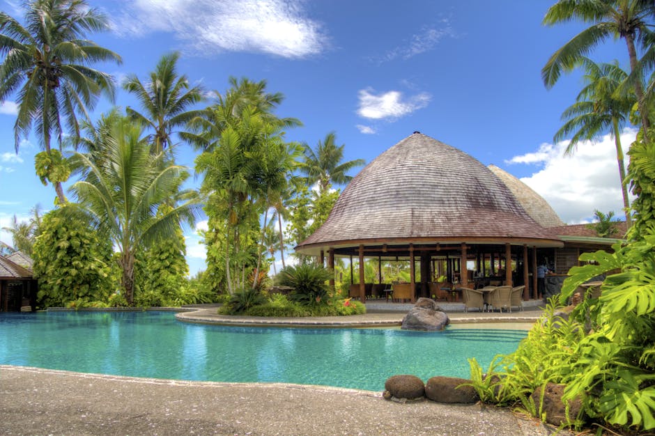 Luxurious tropical resort with a serene pool, lush palm trees, and relaxation area