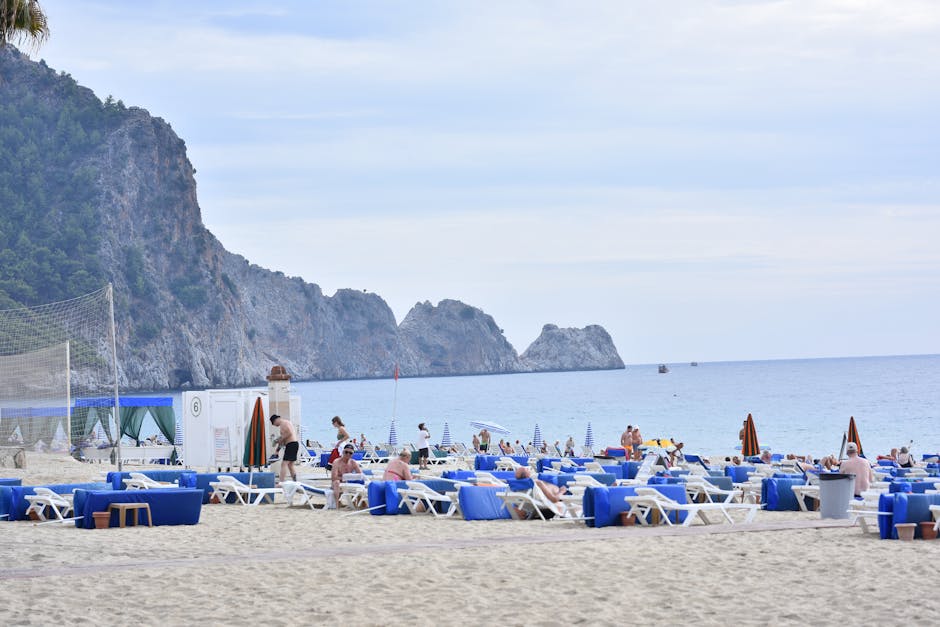 Beautiful sandy beach in Alanya, Turkey with sun loungers and scenic rocky cliffs