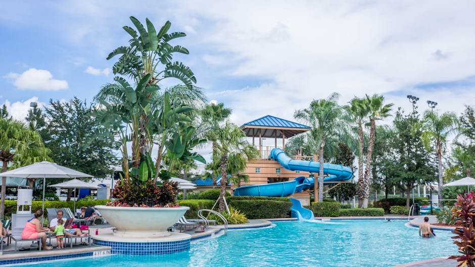 Vibrant tropical resort scene featuring a pool, waterslide, and lush palm trees, ideal for summer vacations