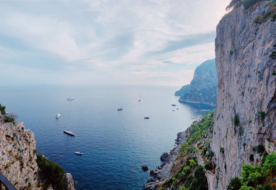 Breathtaking view of Capri cliffs and sailboats on a clear day in Italy